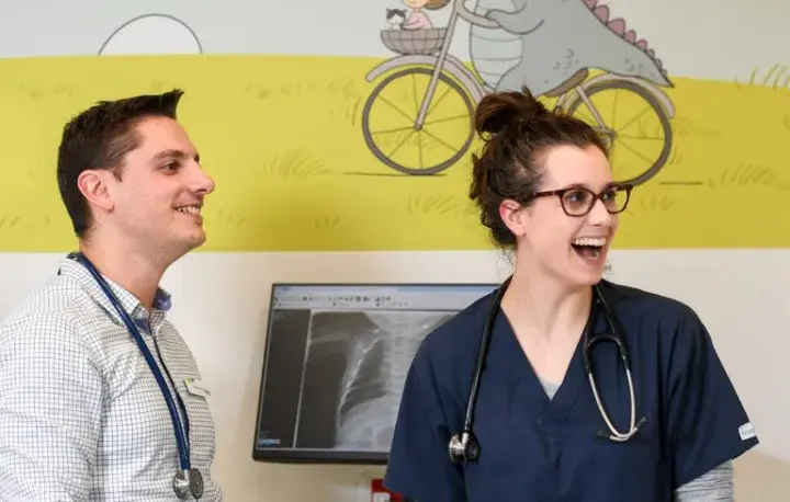 Two junior doctors smiling in a hospital setting. 