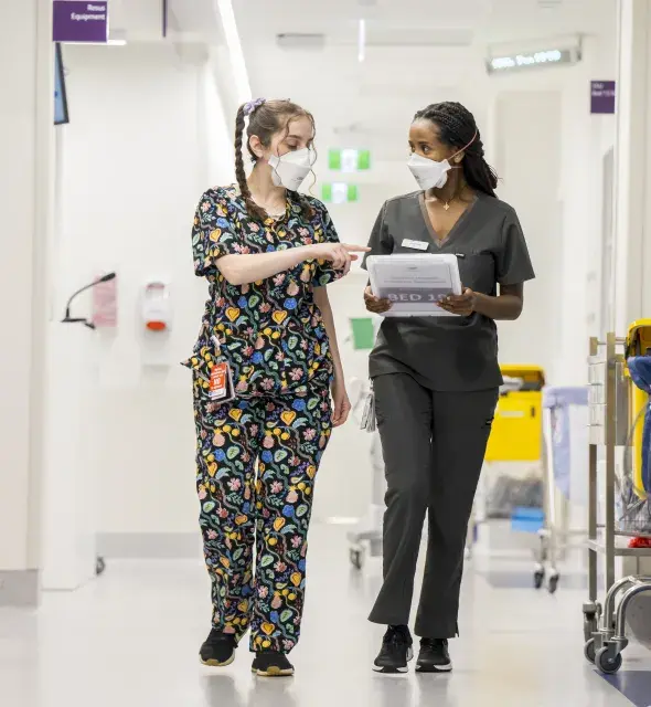 Two Western Health staff members walking and talking in a hospital setting 