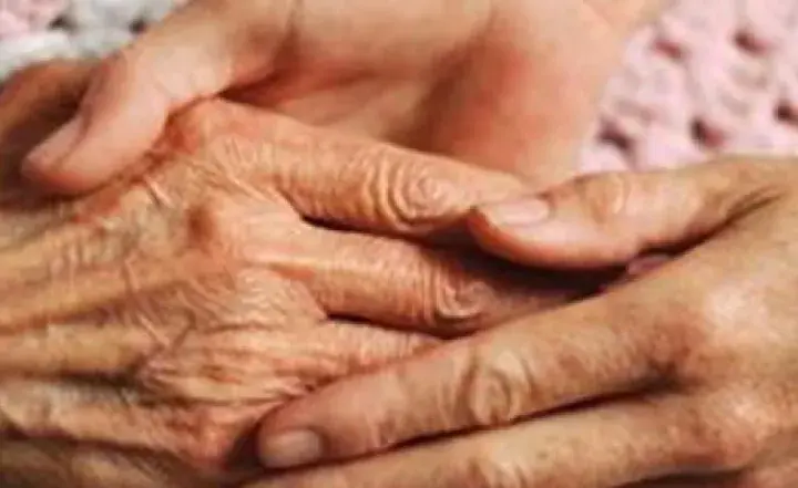 A young person holds an elderly person’s hands with care